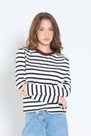 Woman wearing a black and white striped sweater with a maroon collar against a white background