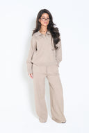 Woman wearing a taupe knit V-neck polo sweater with matching wide-leg knit pants; relaxed, cozy fit.
