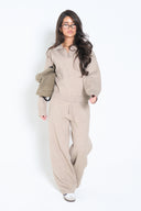 Woman wearing a taupe knit V-neck polo sweater with matching wide-leg knit pants; relaxed, cozy fit.
